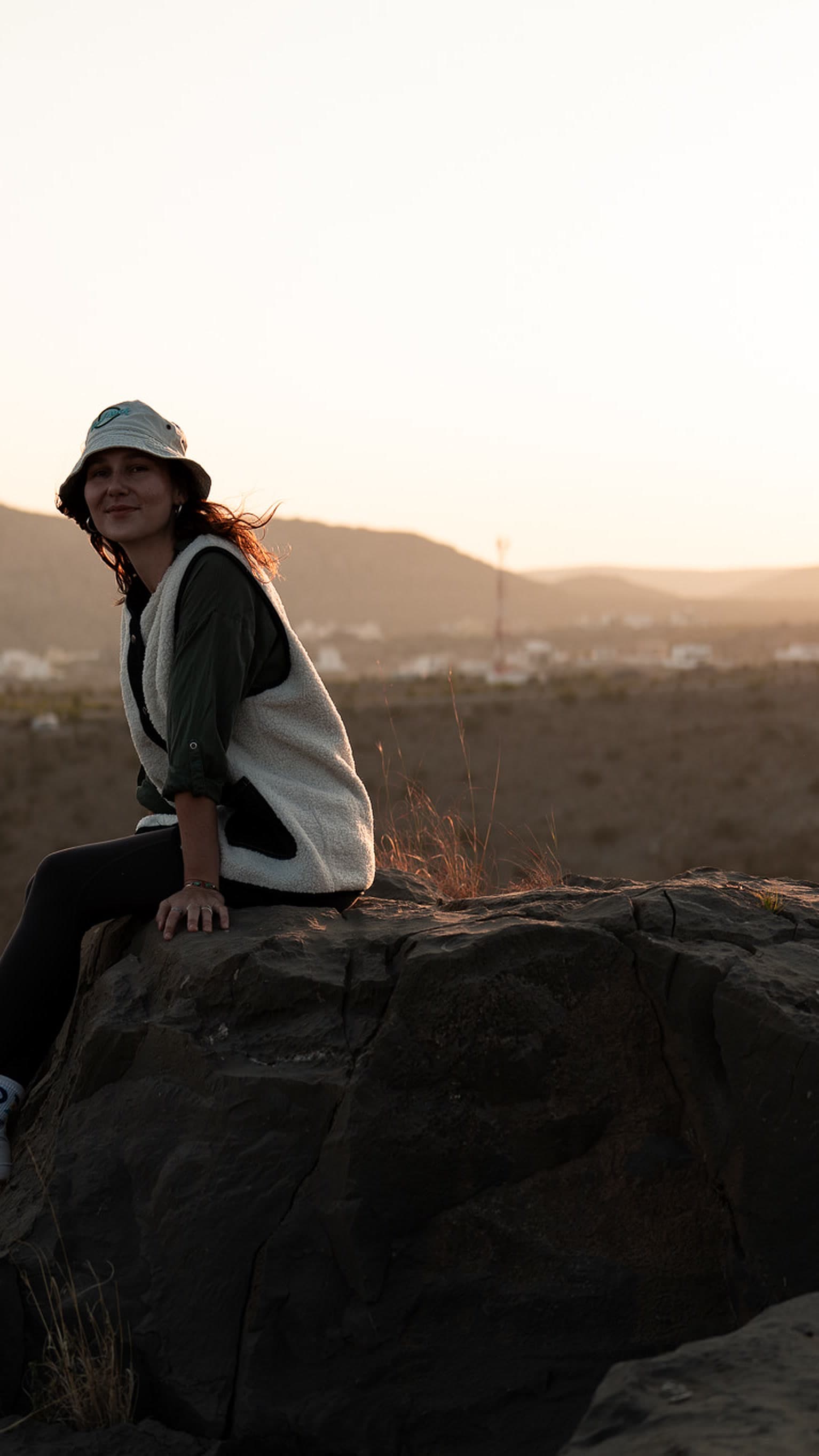 Victoria sitting on a rock at sunset