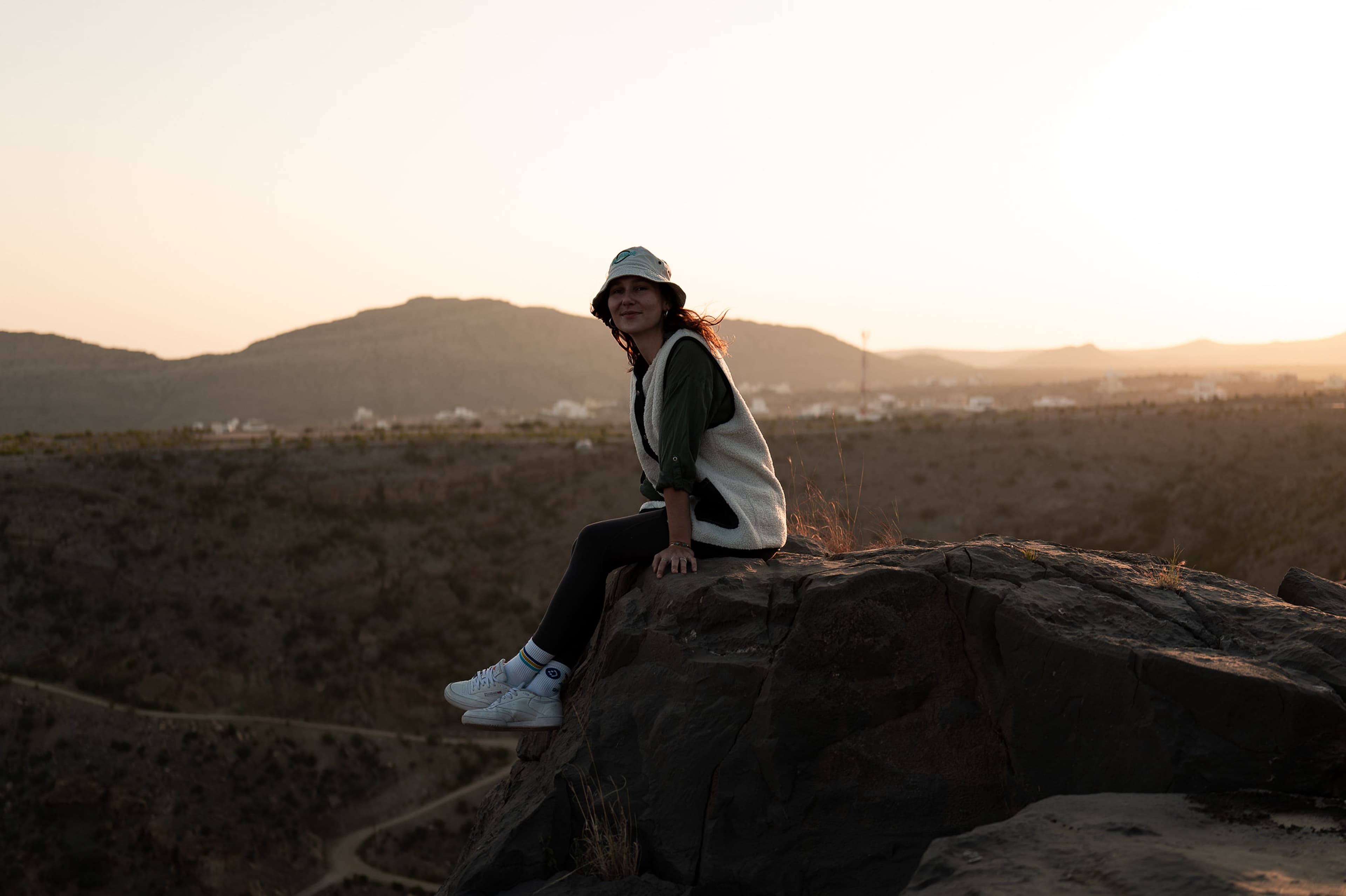 Victoria sitting on a rock at sunset